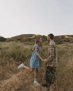 a man and woman holding hands in the middle of a field