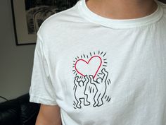 a person wearing a white shirt with a red heart on it