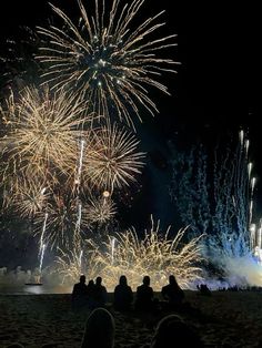 people are sitting on the beach watching fireworks