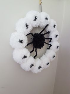 a white wreath with black spider decorations hanging from it's center loop on the wall