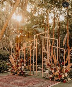 an outdoor ceremony setup with flowers and greenery on the ground in front of trees