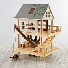 a wooden doll house with stairs and trees on the top floor next to a tree trunk