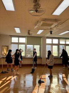 several people in a room with mop's on the floor