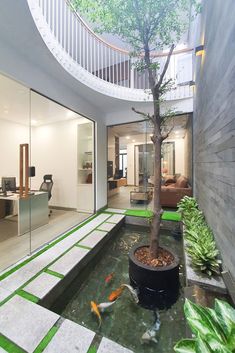 a room with a tree and some fish in the water next to an office building