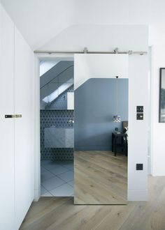 an open glass door leading to a bathroom with blue walls and wood flooring on the side