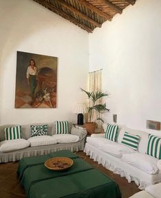 a living room filled with white couches and green striped pillows on top of them