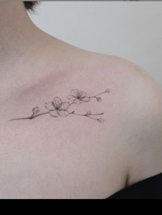 a woman's chest with a small flower tattoo on the left side of her neck