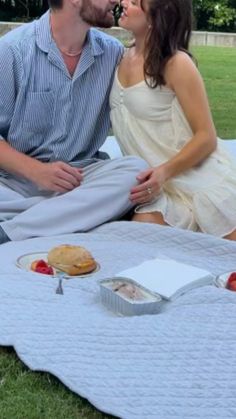 a man and woman sitting on the grass kissing