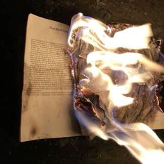 an open book on the ground with fire coming out of it's middle part