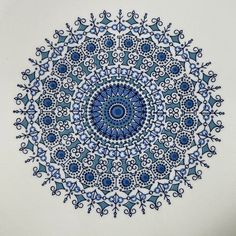 a blue and white plate with an intricate design in the center, on a white surface