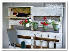 an old wooden pallet with flowers and gardening tools hanging from it's sides