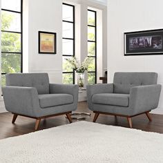 two gray chairs sitting next to each other on a white rug in a living room