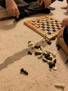 several people sitting on the floor playing a game of checkers and draughts with pieces scattered around them