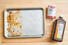 a metal tray with food on it next to a can of soda and a bottle of sauce