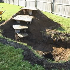 a pile of dirt sitting next to a wheelbarrow on top of a lush green field