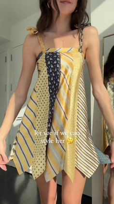 a woman is standing in front of a mirror wearing a dress with ties on it