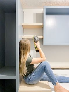 a woman sitting on the floor with a drill in her hand