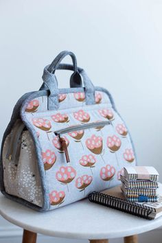 a handbag sitting on top of a table next to books and a book bag