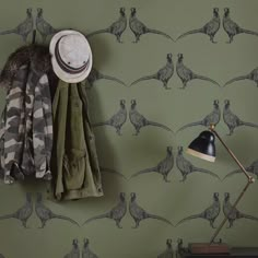 a wall with a coat rack, lamp and hat hanging on it's side