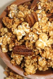 a wooden bowl filled with caramel popcorn and pecans