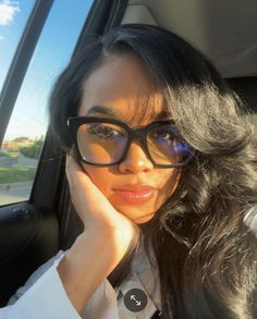 a woman wearing glasses sitting in the back seat of a car