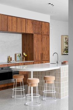 three stools sit at the center of a kitchen island in front of an oven