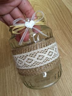 a hand holding a mason jar with twine and ribbon