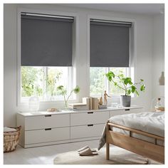 a bedroom with white walls and two windows that have shades on them in the window sill