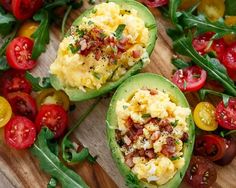 stuffed avocados with eggs and tomatoes on a cutting board next to a bowl of beans