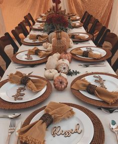 a table set for thanksgiving dinner with pumpkins, gourds and napkins