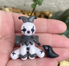 a small white and black figurine sitting on someone's hand