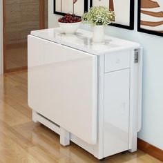 a white cabinet sitting in the middle of a room next to a wall with pictures on it