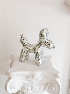 a silver dog statue sitting on top of a white pedestal