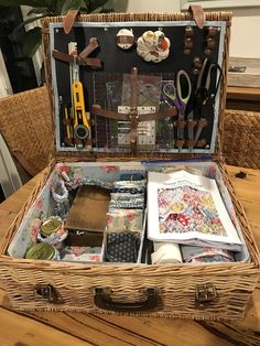 an open suitcase sitting on top of a wooden table filled with crafting supplies and scissors