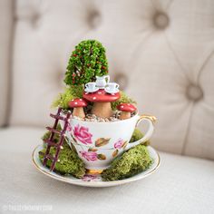 a miniature teacup with a mushroom house in it