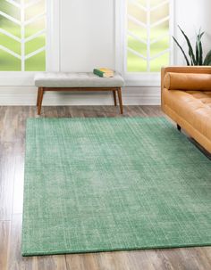 a green rug in a living room next to a couch