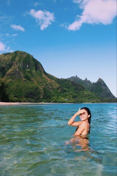 a woman standing in the water with her arms behind her head