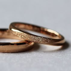 two gold wedding rings sitting next to each other