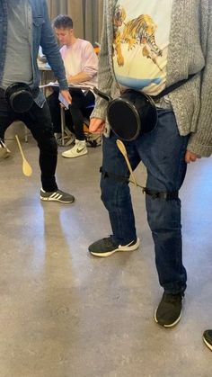 a group of men standing around each other with drums in their hands and wearing knee pads