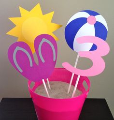 a pink bucket filled with sand and two beach ball toppers sitting next to each other