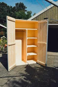 an open wooden cabinet sitting on top of a brick floor next to a garage door