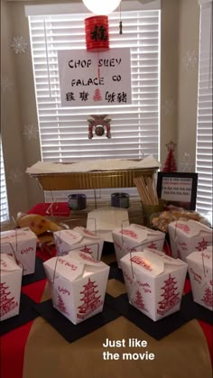 a table topped with lots of white boxes covered in red and white writing next to a sign that says chop suey palace co