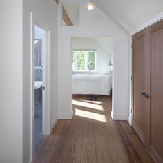 an open door leading to a bedroom with hardwood floors and white walls in the background