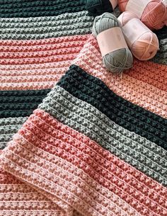 crocheted blanket with balls of yarn on top and two skeins of yarn next to it