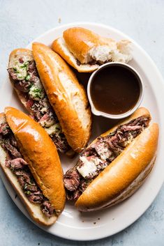 three sandwiches on a plate with dipping sauce