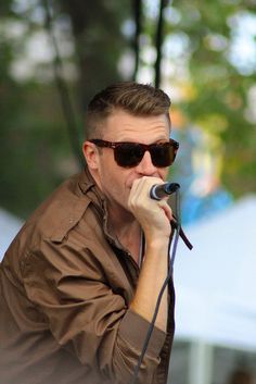 a man with sunglasses on singing into a microphone