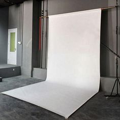 an empty photo studio with white backdrops and lighting equipment on the floor in front of it