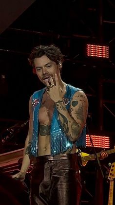 a man with tattoos on his chest standing in front of a microphone