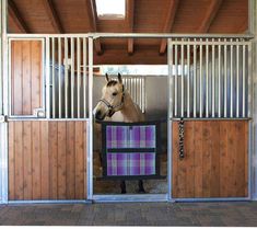 a brown horse standing inside of a stable