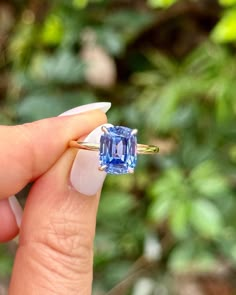 a woman's hand holding an engagement ring with a blue diamond